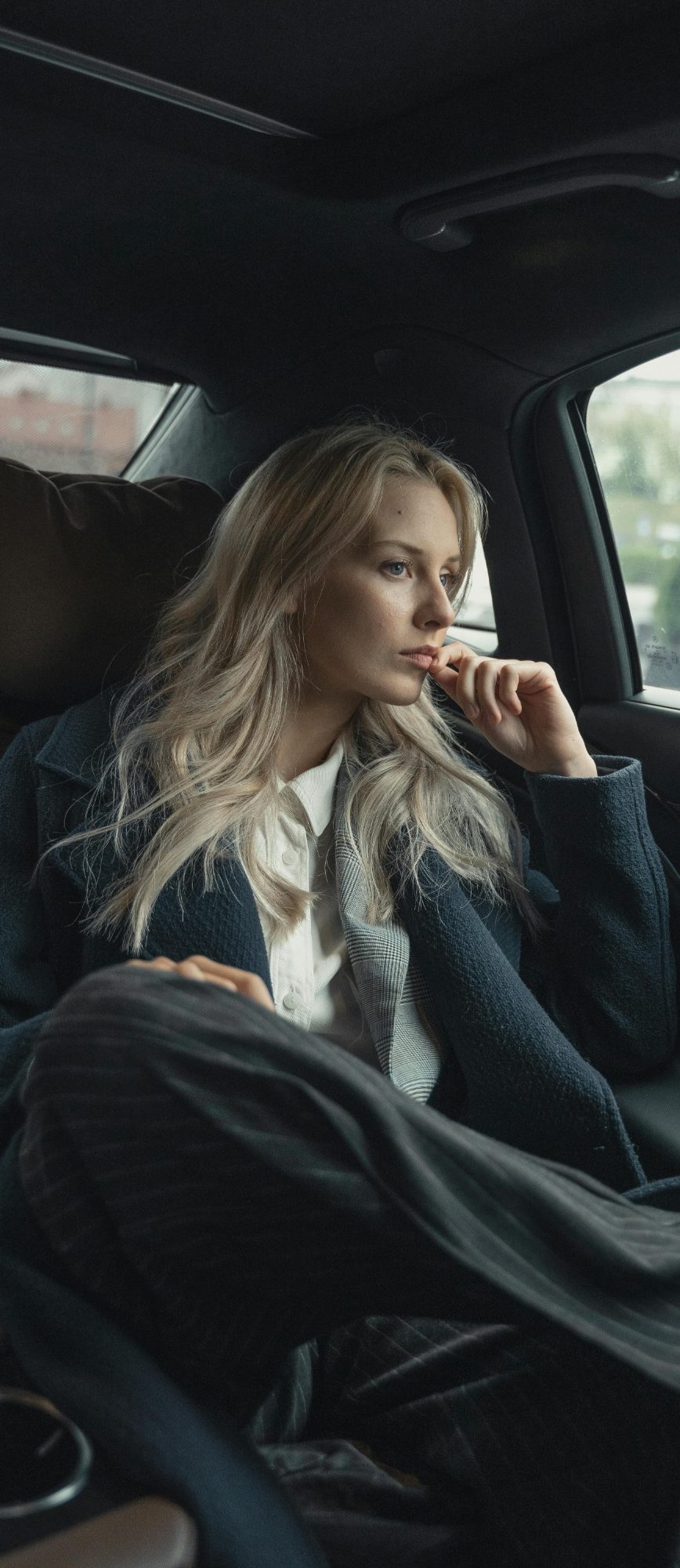 VTC, Taxi, Chauffeur privé Classe-Affaires VTC en Haute-Savoie, Chamonix, Genève et Annecy. Une femme assise dans une voiture, regardant pensivement par la fenêtre.